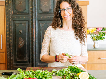 Dr. Erika Siegel in her kitchen, fresh herbs and greens on the counter, the kitchen as a healing space