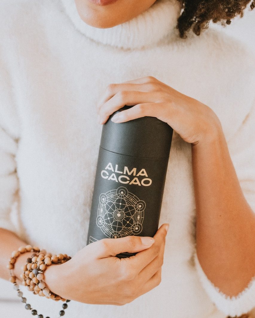 A woman holding a tin of Alma Cacao ceremonial cacao as a gift