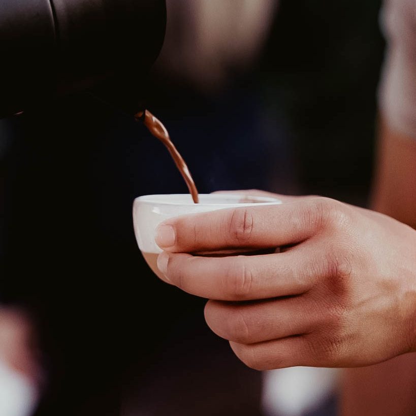 Pouring ceremonial cacao into a small cup at a ceremony